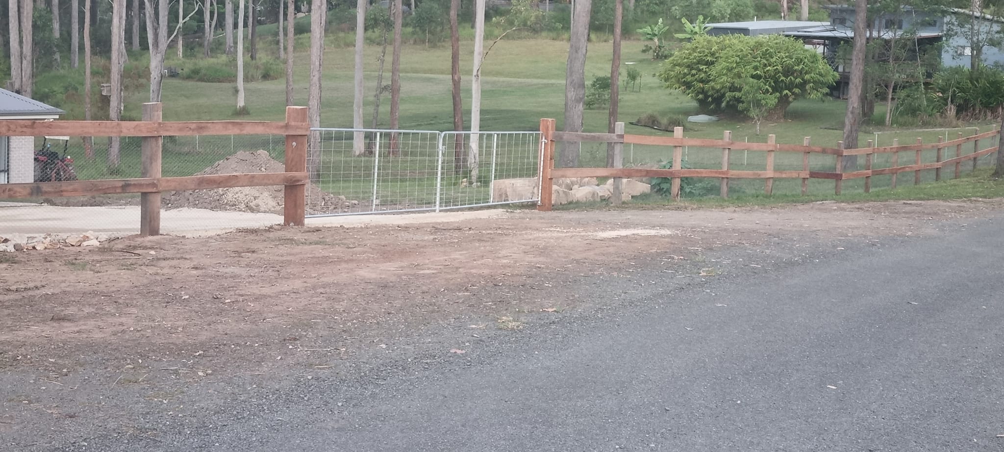 Post and rail fence with farm gate, gum trees behind
